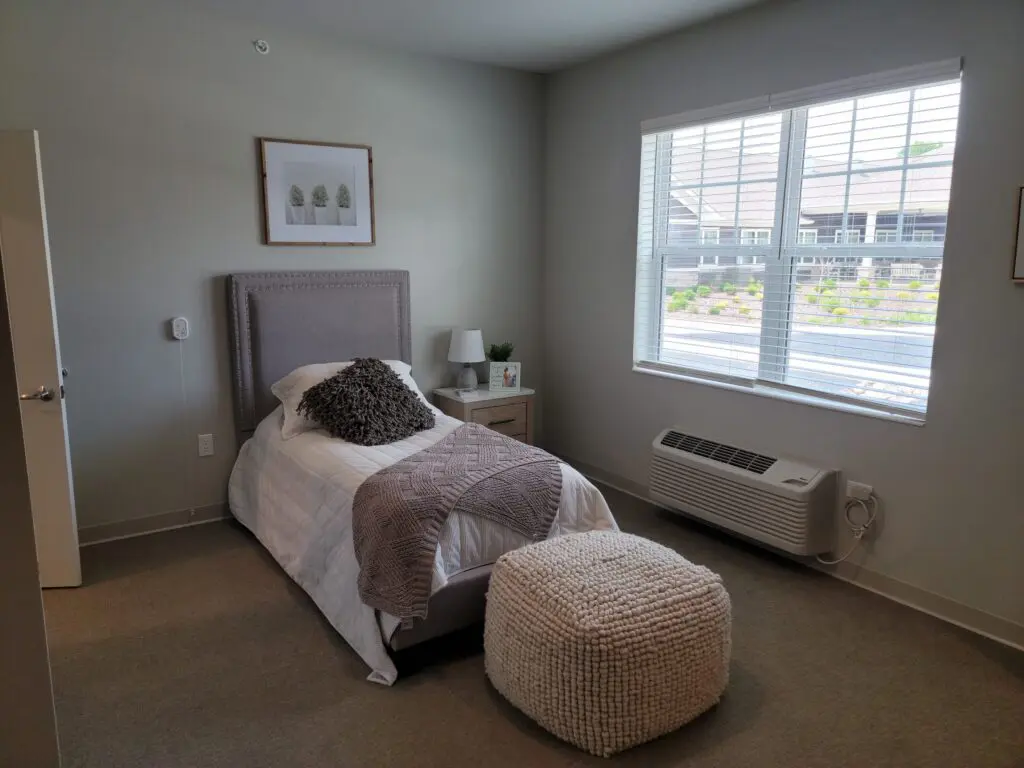furnished room with single bed and ottoman