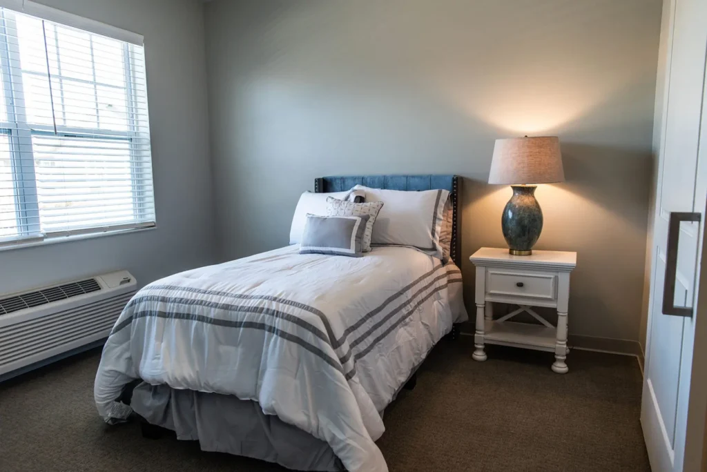 furnished bedroom with single bed, bedside table, and lamp
