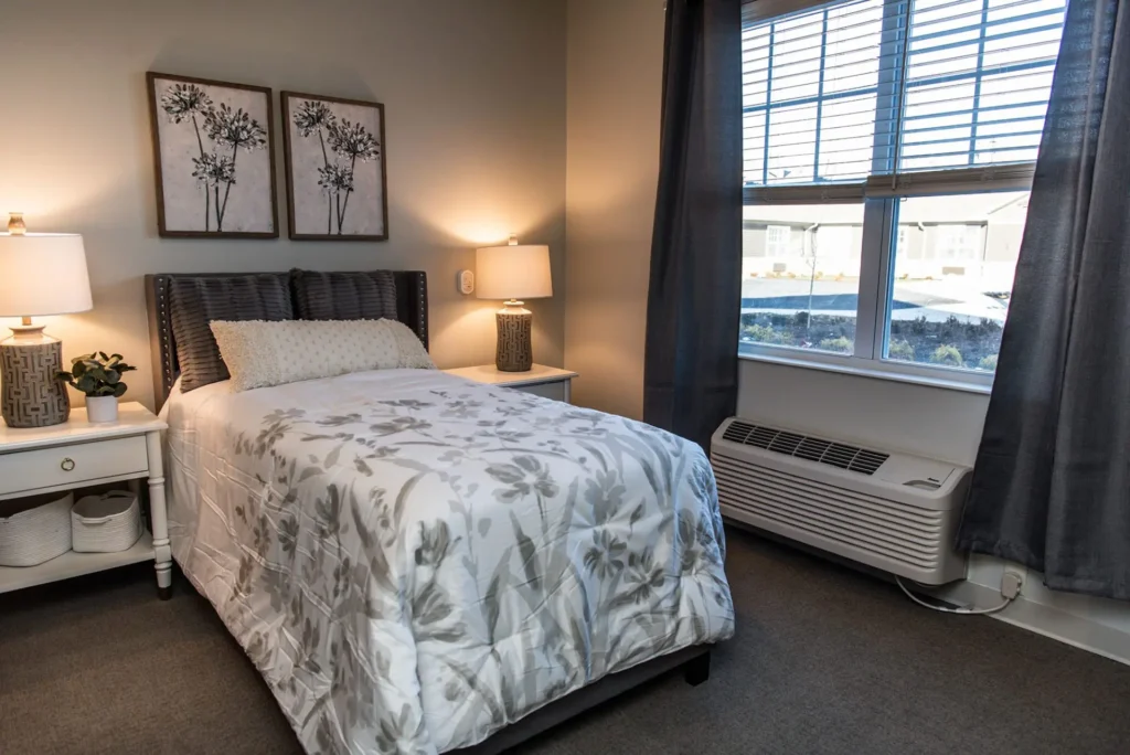 furnished bedroom with two side tables, lamps, and view of windows